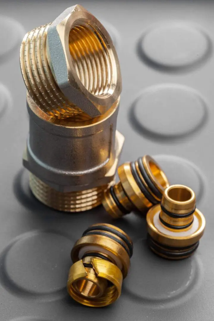 Close-up of brass threaded fittings and rings on a gray surface.